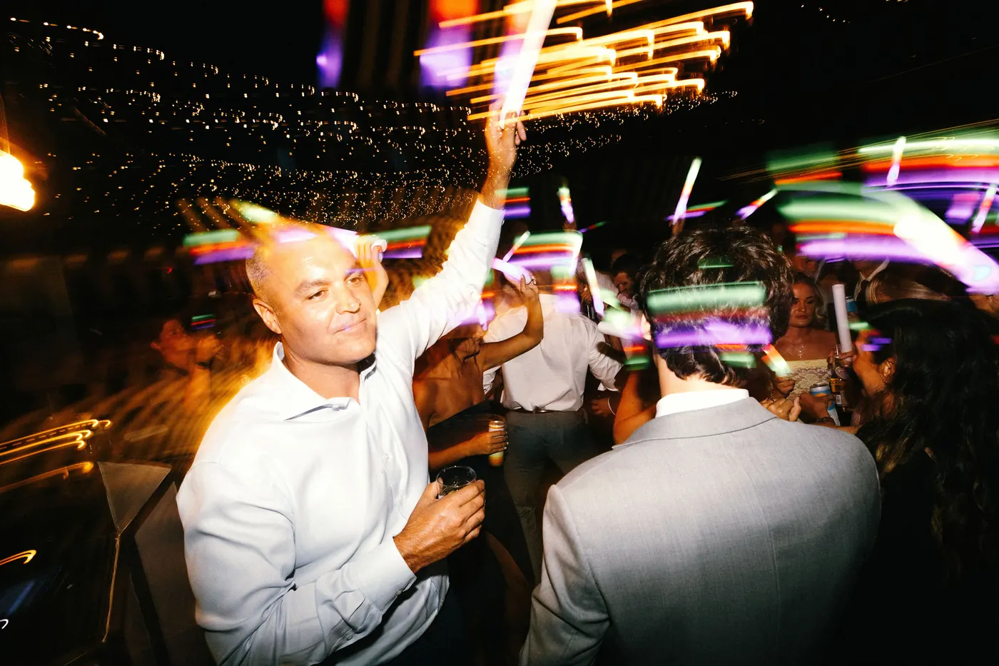 A guest dancing under colorful party lights
