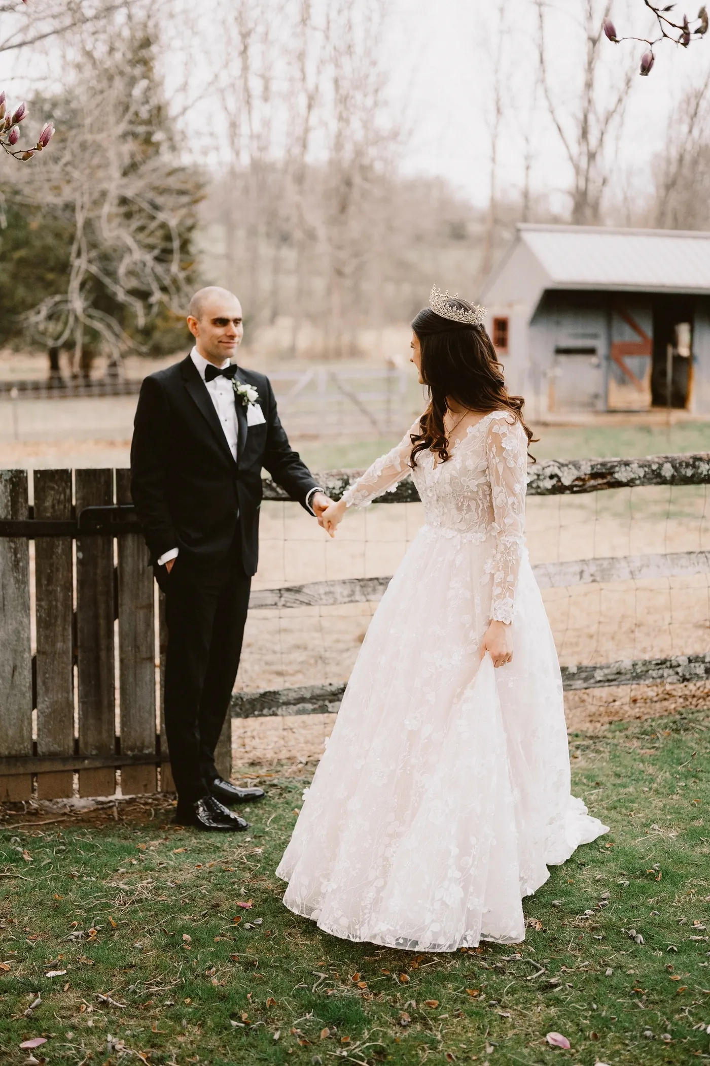 Steve and Maria holding hands beside the farm fence