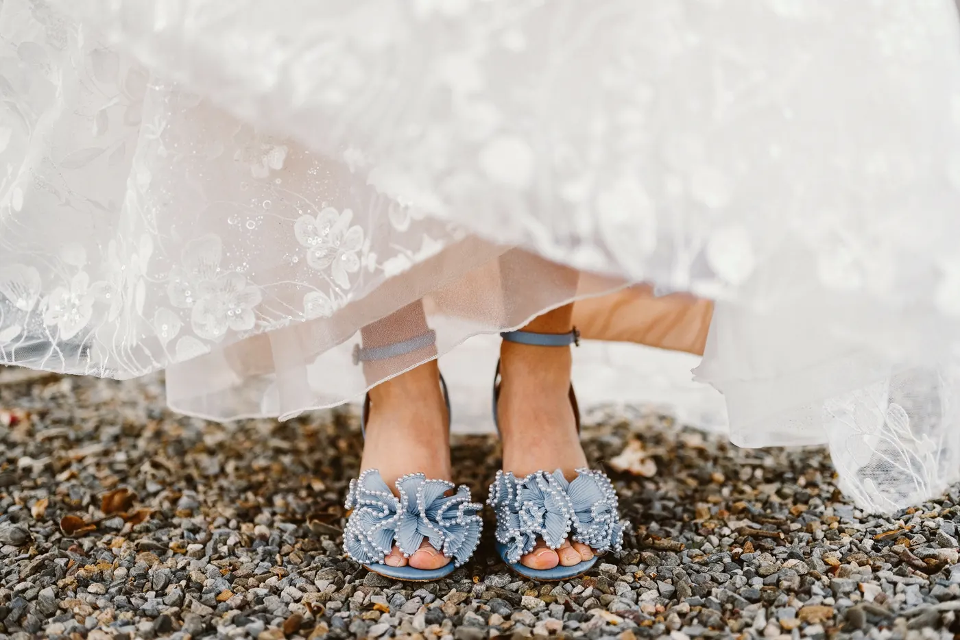 Maria's blue ruffled wedding shoes peeking out from her lace gown