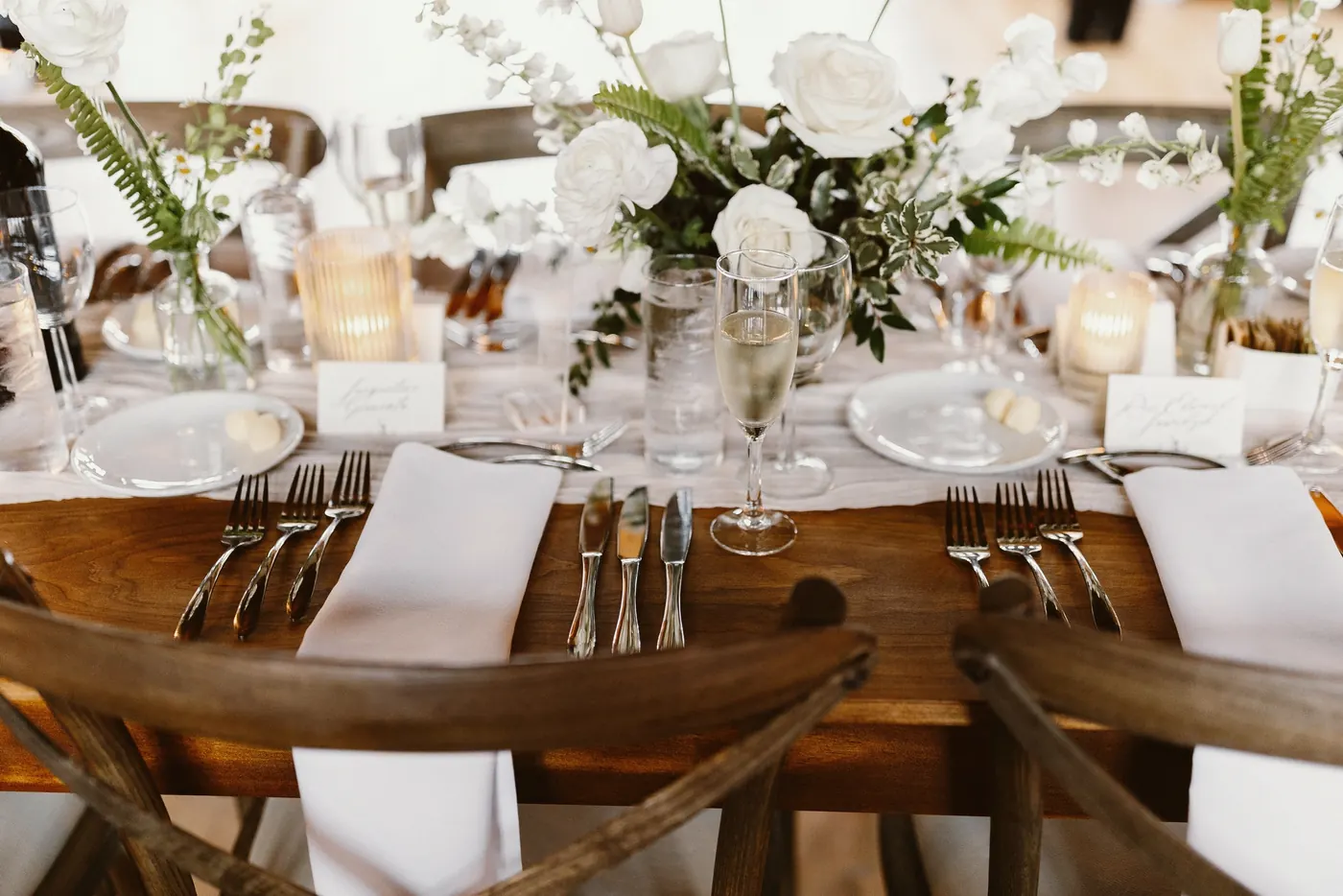 Reception place settings with white roses and candlelight